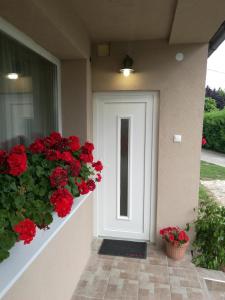 a white door on a house with red flowers at Virágos Apartman Balatonszemes in Balatonszemes