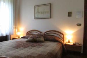 a bedroom with a bed and two lamps on tables at Albergo Alla Trota in Pulfero