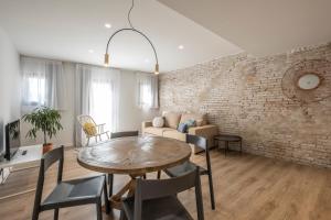 a living room with a table and a brick wall at Cliper Apartments by Escampa Hotels in Platja d'Aro