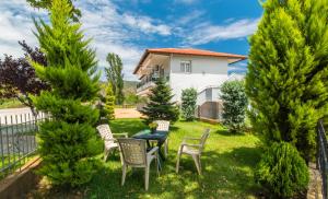 a yard with chairs and a table and trees at A Ponte Studios & Apartments in Sykia Chalkidikis