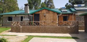 a house with a green roof and a wooden fence at Ngomongo in Nanyuki