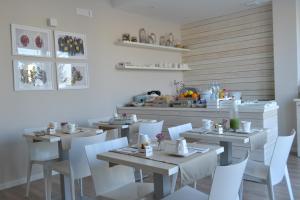 une salle à manger avec des tables et des chaises blanches dans l'établissement Gatto Bianco Le Terrazze, à Bari