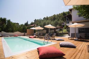 a swimming pool with pillows and umbrellas on a wooden deck at Casa Luxury Suites in Paliouri