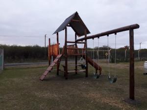 un parque infantil de madera con tobogán y columpios en Piraka´s en Gualeguaychú