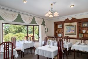 a dining room with white tables and chairs and a window at Kathleens Country House in Killarney