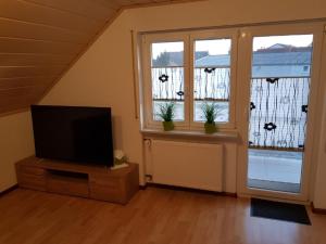ein Wohnzimmer mit einem TV und 2 Fenstern in der Unterkunft Ferienwohnung Witt in Rheinhausen