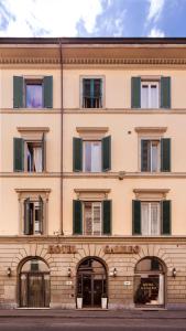 un edificio abbronzato con finestre con persiane verdi di Hotel Galileo a Firenze