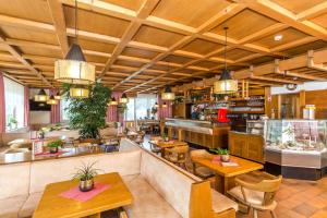 un ristorante con soffitti e tavoli in legno e sedie di Hotel Alpenrose Dolomites a La Valle
