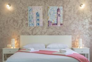Cette chambre comprend un lit blanc avec deux tables et deux photos sur le mur. dans l'établissement Villa Nave, à Zaton
