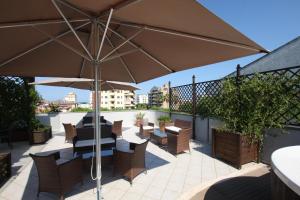 um pátio com uma mesa, cadeiras e um guarda-sol em Hotel Naxos B&B em Alba Adriatica