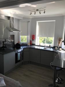 a kitchen with black and white appliances and two windows at Berkshire Serviced Apartment Helena 12 in Reading