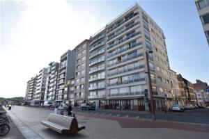 a large building with people sitting on a bench in front of it at Appartement Knokke-Heist in Knokke-Heist