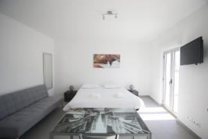 um quarto branco com uma cama e uma mesa de vidro em Guest House Lovely Swan em Lagos