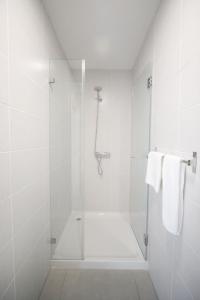 bagno bianco con doccia e asciugamani bianchi di Guest House Lovely Swan a Lagos Altre 16 foto