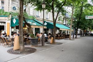 a group of people sitting at tables at an outdoor restaurant at Veeve - Batignolles Balcony in Paris
