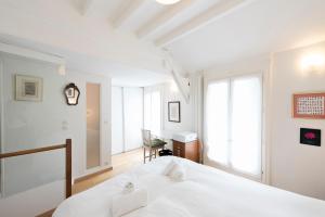 a white bedroom with a bed and a desk at Veeve - Batignolles Balcony in Paris