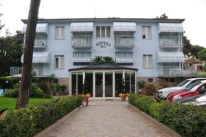 a white building with cars parked in front of it at Hotel Riviera Blu in Tirrenia