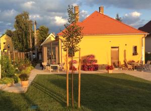 a yellow house with a tree in the yard at Furedi virag villa in Balatonfüred