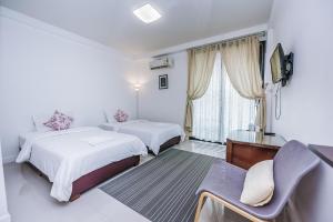 una habitación de hotel con 2 camas y una silla en Bandahara, en Satun