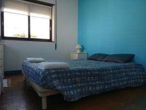 Dormitorio azul con cama y ventana en Casa da Figueira Da Foz, en Figueira da Foz