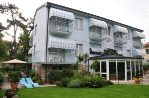 a white building with balconies and a yard at Hotel Riviera Blu in Tirrenia