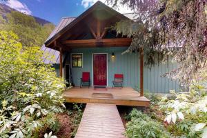 una casa verde con 2 sillas en un porche de madera en Snowbird Chalet #5 en Girdwood