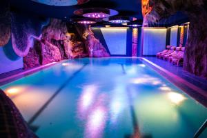uma piscina numa gruta com luzes roxas em Hotel Mirabello - Slow Hotel Benessere em Fiera di Primiero