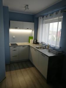 una cucina con armadi bianchi, lavandino e finestra di TESTO Apartments a Mielno
