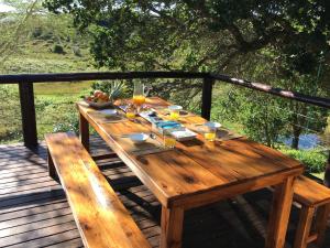 Nkumbe Bush Retreat Family Home في Ponta Malangane: طاولة خشبية مع كؤوس من النبيذ على سطح السفينة