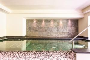 a pool in a room with a stone wall at Hotel Garnì Paradisi - Wellness & Spa in Mezzano