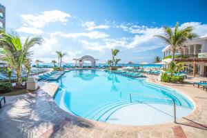 a large swimming pool at a resort with palm trees at Wyndham Alltra Cancun All Inclusive Resort in Cancún