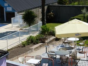 eine Terrasse mit Tischen, Stühlen und einem Sonnenschirm in der Unterkunft Hotel Des Bains in Saint-Jean-le-Thomas