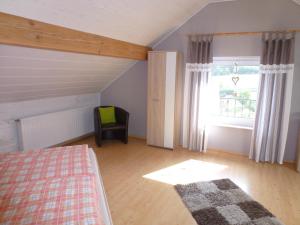 a bedroom with a bed and a window and a chair at Ferienwohnung Familie Schultheis in Marjoß