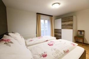 a bed with white sheets and pink flowers on it at Apartment Am Bach in Mellau