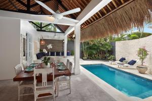 a dining room with a table and a swimming pool at Villa Elleo in Seminyak