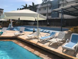 a group of chairs and an umbrella next to a pool at Cafe e Almoço Hotel Thermas da Affego in Caldas Novas