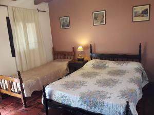 a bedroom with two beds and a lamp on a table at Hostal Rustyk in Cafayate