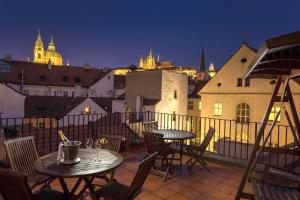 2 mesas y sillas en un balcón por la noche en Hotel Pod Věží en Praga