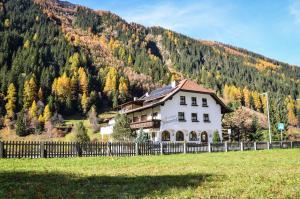 a house in front of a mountain with a fence at Sonnenhof - Apartments & Zimmer in Kaunertal