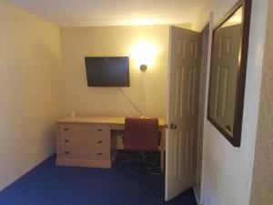 a room with a desk with a television and a chair at La Casa Inn and Suites in Tallahassee