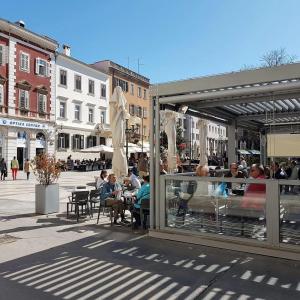 a group of people sitting at tables on a city street at Fran Center Apartments (Square) in Pula