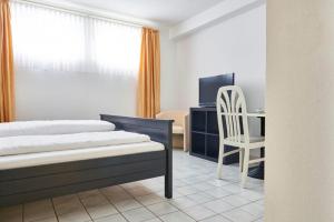 Hotel Asslar في Aßlar: غرفة نوم بسرير ومكتب وكرسي