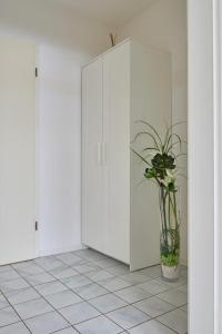 ein weißer Schrank mit einer Topfpflanze in einem Raum in der Unterkunft Hotel Asslar in Aßlar