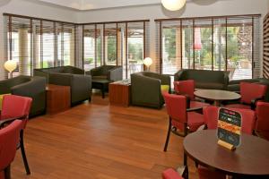 una sala de espera con mesas, sillas y ventanas en Hotel ibis Setubal en Setúbal