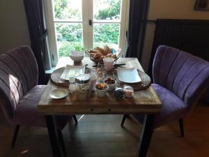 a table with food on it with two purple chairs at Het geheim van Merselo in Merselo