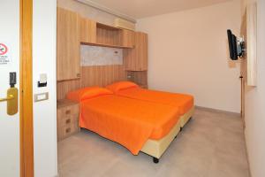 a bedroom with a bed with orange sheets and orange pillows at Hotel Lidia in Alba Adriatica