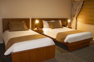 a hotel room with two beds and two lamps at Hotel Carolina Montecarlo in Quito