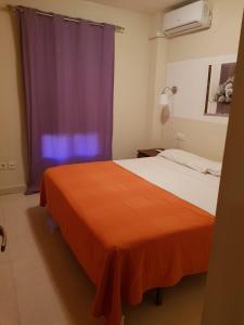 ネルハにあるApartamento Cala de Nerja IIのベッドルーム1室(オレンジ色の毛布付きのベッド1台付)