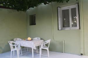 una mesa con sillas blancas y una ventana en Mulberry Home, en Likotinaréa