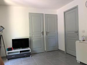 a living room with two doors and a tv at Mazet « Domaine de la pinède » in Le Lavandou